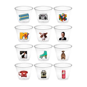 May include: Twelve clear plastic cups with various 1980s themed images printed on them. The images include a Blockbuster Video ticket, a boombox, a Rubik's Cube, the MTV logo, a character from the movie E.T., a photo of Ronald Reagan, roller skates, a red rotary phone, an instant camera, and a can of Jolt Cola.