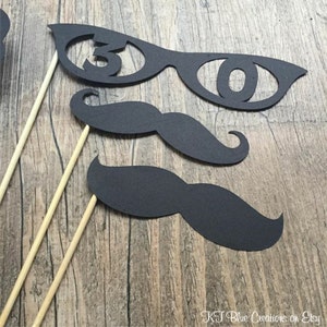 May include: Three black photo booth props on wooden sticks. The props are a pair of glasses with the number 30 cut out, and two different sized black mustaches.