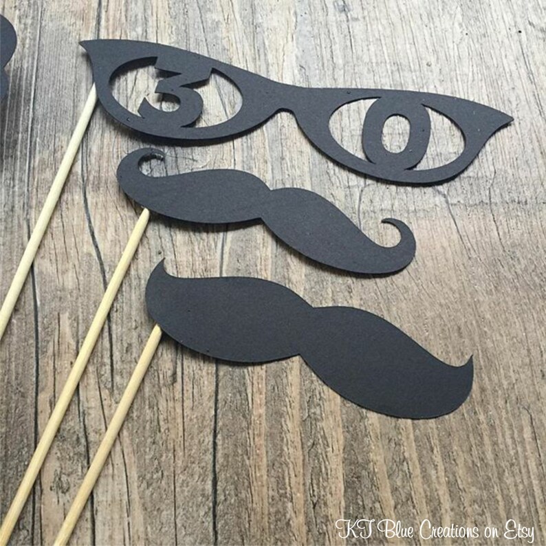 May include: Three black photo booth props on wooden sticks. The props are a pair of glasses with the number 30 cut out, and two different sized black mustaches.