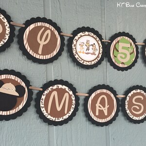 May include: A brown, black, and green banner with the letters "D", "P", "5", "M", "A", "S", and a cartoon image of Mickey Mouse wearing a safari hat. The banner is decorated with a zebra stripe pattern and leopard print.