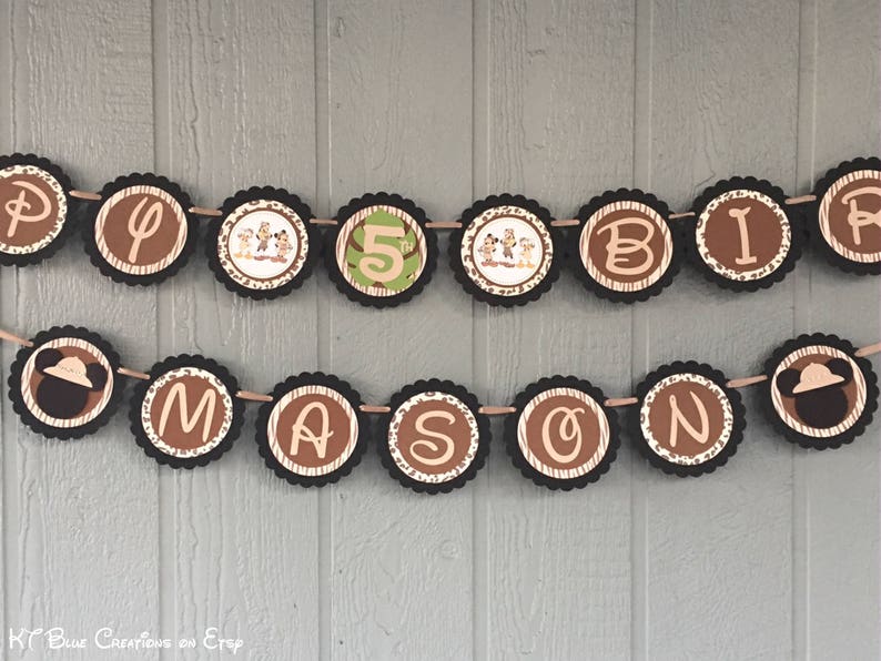 May include: A brown and tan birthday banner with the letters "Happy" and "Birthday" and the number "5" in the center. The banner is decorated with jungle animal characters and a jungle-themed pattern.