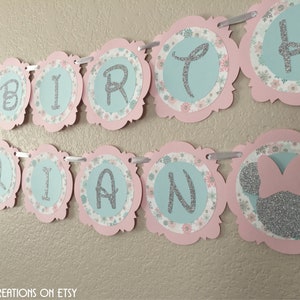 May include: A pink and blue birthday banner with the word "BIRTHDAY" and a silver glitter Minnie Mouse head.