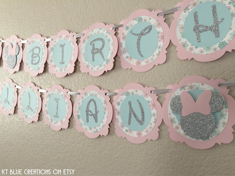 May include: A pink and blue birthday banner with the word "BIRTHDAY" and a silver glitter Minnie Mouse head.
