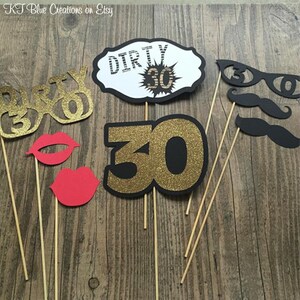 May include: A set of 7 black and gold photo booth props for a 30th birthday party. The props include a pair of glasses that say "Dirty 30", a large number "30" with gold glitter, a pair of lips, a mustache, and a sign that says "Dirty 30".
