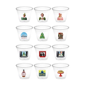 May include: A collection of clear plastic shot glasses, each adorned with a different image. The images include characters from the movie Elf, New York City, a Christmas tree, and a cake. Some glasses have text that reads "World's Best Cup of Coffee".
