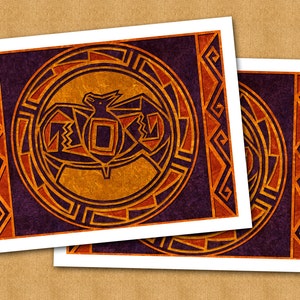 May include: Two printed cards with a geometric design featuring a stylized bat in a circle. The bat is orange and black, and the circle is surrounded by a red and orange geometric pattern. The background is purple.