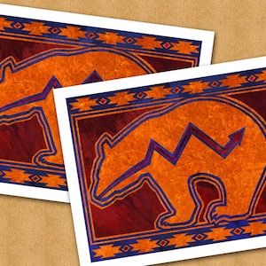 May include: Two prints of a stylized orange bear with a blue outline on a red, orange, and blue patterned background.
