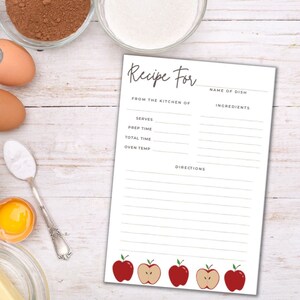 Puede incluir: Una tarjeta de receta imprimible con fondo blanco y líneas verdes. La tarjeta tiene un título que dice "Receta para" y secciones para el nombre del plato, los ingredientes, las porciones, el tiempo de preparación, el tiempo total, la temperatura del horno y las instrucciones. La parte inferior de la tarjeta tiene una fila de cinco manzanas rojas.