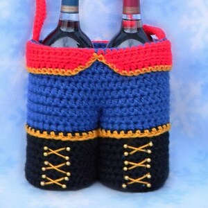 May include: Crocheted wine bottle carrier shaped like a pair of blue pants with red suspenders, black boots, and gold accents.