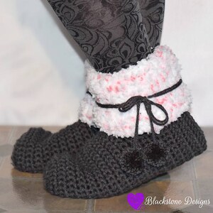 May include: Dark gray crocheted slipper boots with a fluffy white and pink trim. The boots have a black tie closure with two small pom-poms. The boots are designed to keep feet warm and cozy.
