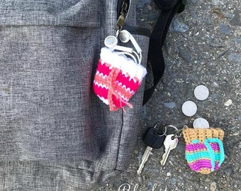 Può includere: Due borse all'uncinetto con strisce colorate. Una borsa è rosa e bianca ed è attaccata a uno zaino grigio. L'altra borsa è rosa, turchese e viola ed è attaccata a un portachiavi. Le borse sono piccole e sarebbero perfette per contenere piccoli oggetti come monete o chiavi.