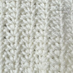 Könnte beinhalten: Nahaufnahme eines weißen gehäkelten Stoffes mit einem strukturierten Muster. Der Stoff hat eine gewebte Optik und ist aus einfarbigem Garn gefertigt.