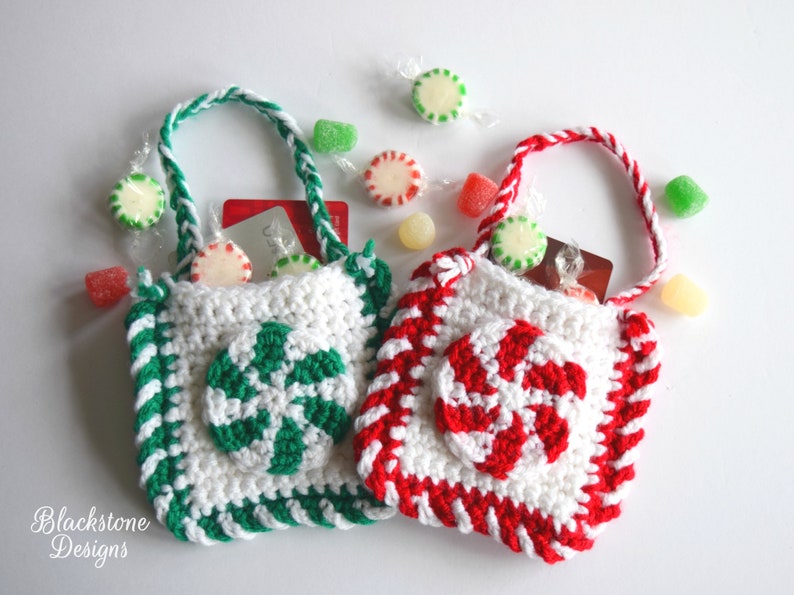 May include: Two small crocheted gift bags with candy cane designs. One bag is red and white, the other is green and white. Both bags have white handles and are filled with candy.
