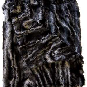 Könnte beinhalten: Eine schwarze und graue Kunstfell-Decke mit einem wellenförmigen Muster. Die Decke ist in der Hälfte gefaltet und hat eine weiche, plüschige Textur.