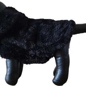 Könnte beinhalten: Schwarzer Kunstfellmantel für kleine Hunde. Der Mantel ist aus weichem, plüschigem Fell und hat ein klassisches Design.