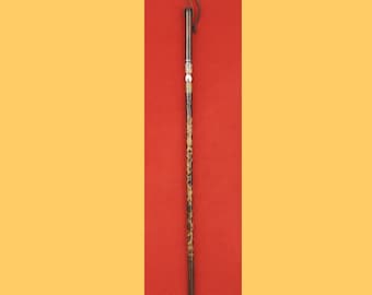 May include: A decorative walking cane with a black and silver handle and a shaft featuring a leopard print design. The cane has a black tip and a loop at the top. The background is red and yellow.