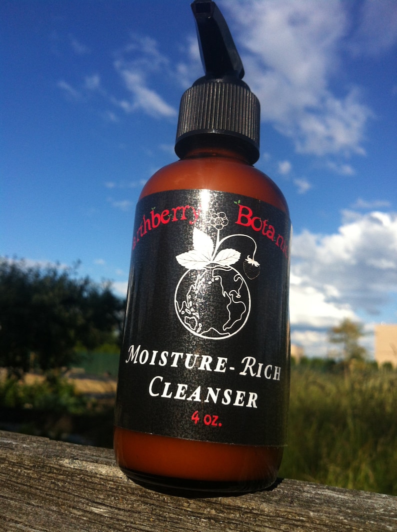 K&ouml;nnte beinhalten: Eine braune Flasche mit schwarzem Pumpspender und schwarzem Etikett. Das Etikett tr&auml;gt einen wei&szlig;en Text mit der Aufschrift "Earthberry Botanics Moisture-Rich Cleanser 4 oz.".