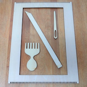 May include: A wooden loom with a comb, needle, and a long wooden tool. The loom is made of light wood and has a white frame.