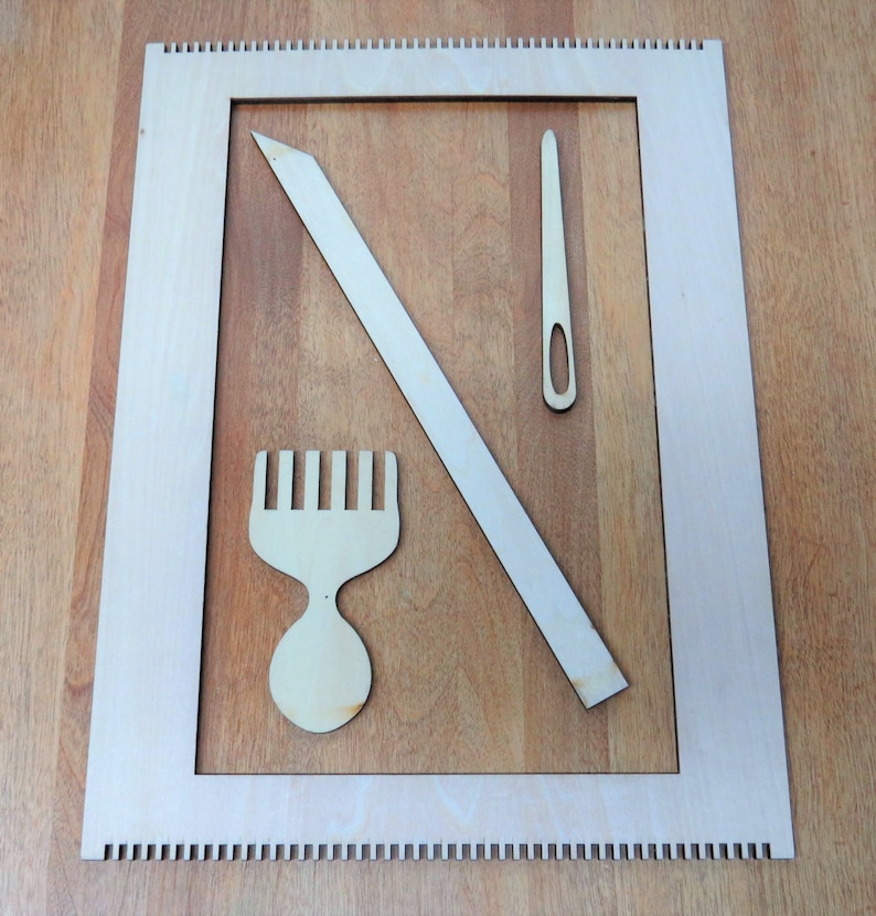 May include: A wooden loom with a comb, needle, and a long wooden tool. The loom is made of light wood and has a white frame.