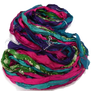May include: A bundle of colorful silk ribbon in shades of pink, teal, green, and purple. The ribbon is frayed and has a vintage look.