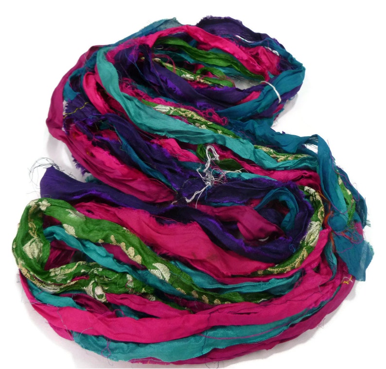 May include: A bundle of colorful silk ribbon in shades of pink, teal, green, and purple. The ribbon is frayed and has a vintage look.