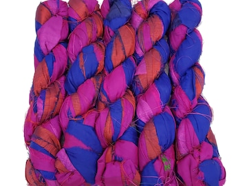 Può includere: Matassa di filato intrecciato nei toni del fucsia, blu e arancione. Il filato è realizzato in seta e ha un aspetto strutturato. I filamenti sono intrecciati strettamente, creando un pezzo spesso e decorativo. Adatto a vari progetti artigianali.