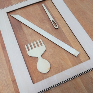 May include: A wooden loom with a wooden comb, needle, and shuttle. The loom is made of light wood and has a white frame. The comb, needle, and shuttle are also made of light wood.