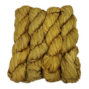 May include: Close-up of a bundle of golden-brown yarn, tightly woven and textured. The yarn appears to be made of ribbon-like strands, creating a braided effect. The color is a warm, earthy tone, suitable for various crafting projects.