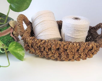 May include: Two spools of white cotton twine in a brown wicker basket. The basket has a woven design and two handles.
