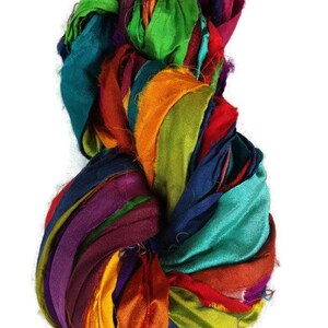 May include: A bundle of colorful silk ribbon scraps in shades of teal, orange, purple, green, and red. The ribbon is arranged in a loose, circular shape.