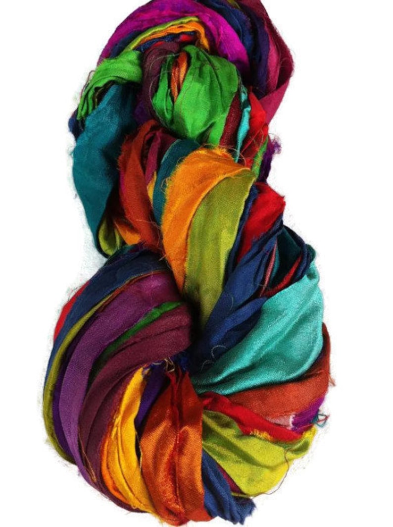 May include: A bundle of colorful silk ribbon scraps in shades of teal, orange, purple, green, and red. The ribbon is arranged in a loose, circular shape.