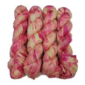 May include: Four skeins of pink and yellow silk ribbon yarn. The yarn is twisted and ready for crafting.