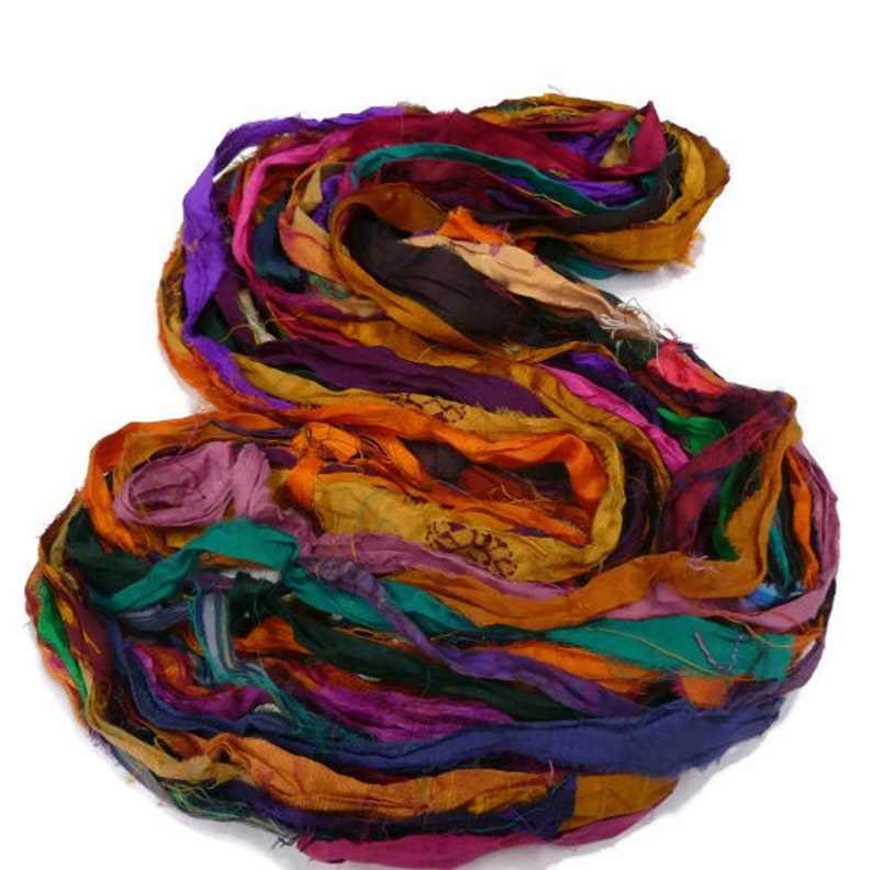 May include: A pile of colorful silk ribbon scraps in shades of orange, purple, green, and blue. The ribbon is perfect for crafting and adding a touch of whimsy to projects.