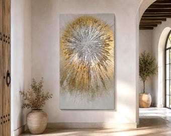 May include: A large rectangular wall art piece featuring an abstract sunburst design. The center is composed of textured silver and white paint strokes radiating outward, surrounded by layers of metallic gold paint on a neutral off-white background.
