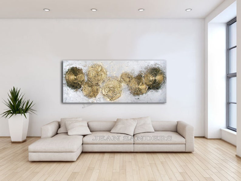 May include: Abstract painting with a white background and gold circles. The circles are layered and overlapping, creating a sense of depth and movement. The painting is framed and ready to hang.