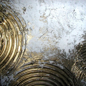 May include: Abstract painting with a textured, white background and gold concentric circles. The circles are raised and have a metallic sheen.