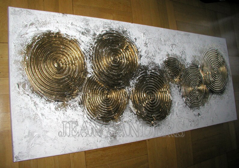 May include: Abstract painting on canvas with a white background and gold concentric circles. The circles are raised and textured, creating a 3D effect.