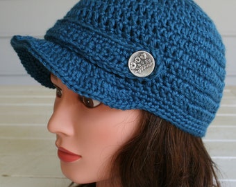 A blue summer cap with a stylish visor.  Crocheted with a Soft ShimmeryTeal Blue Yarn and finished off with a buttoned brim.