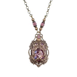 May include: A delicate gold necklace with a pink and purple iridescent glass pendant set in an ornate filigree frame.