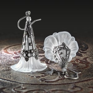 Lucite flower earrings in frosted white with antiqued silver filigree cones photographed on a vintage brown background