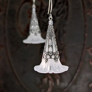 Lucite flower earrings in frosted white with antiqued silver filigree cones photographed on a vintage brown background