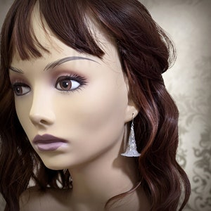 Lucite flower earrings in frosted white with antiqued silver filigree cones photographed on a mannequin