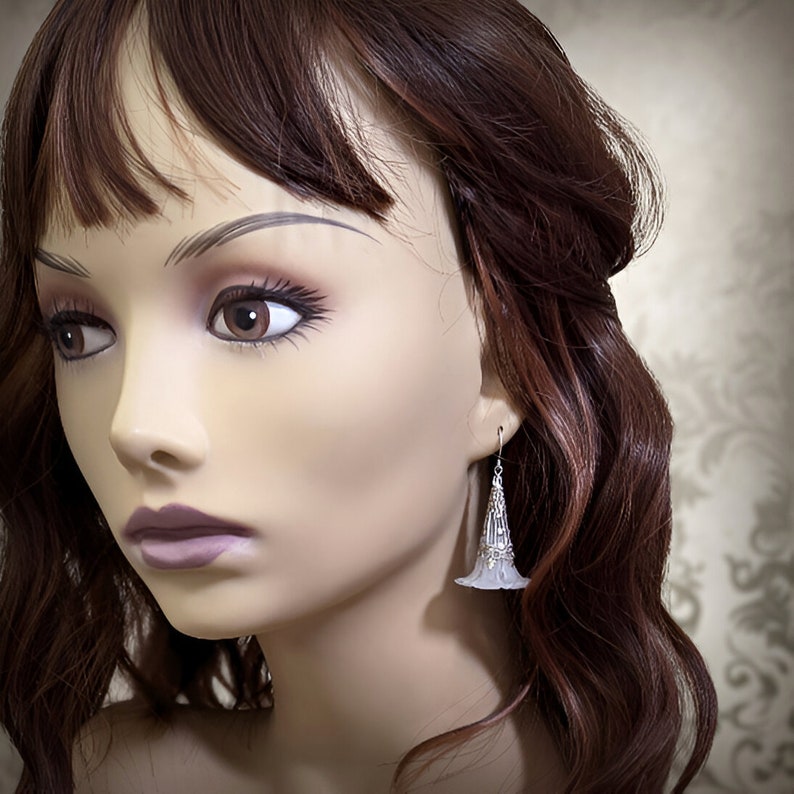 Lucite flower earrings in frosted white with antiqued silver filigree cones photographed on a mannequin