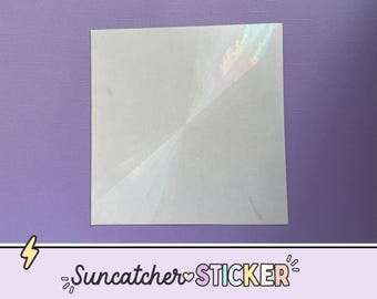 May include: A square, white suncatcher sticker with iridescent rainbow highlights. The sticker is on a purple background. The text "Suncatcher STICKER" is at the bottom of the image.