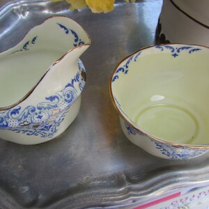 May include: Two white ceramic bowls with blue and gold floral designs. The bowls are on a silver tray.