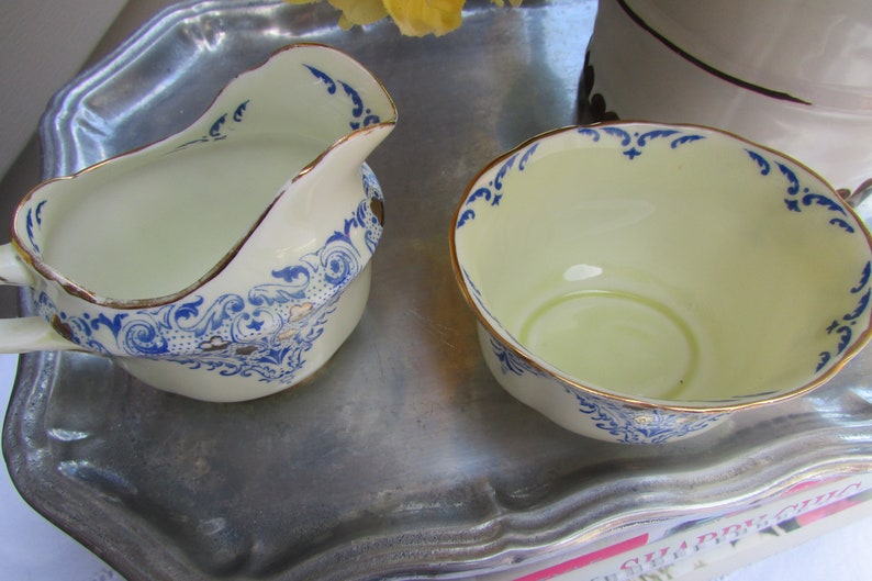 May include: Two white ceramic bowls with blue and gold floral designs. The bowls are on a silver tray.