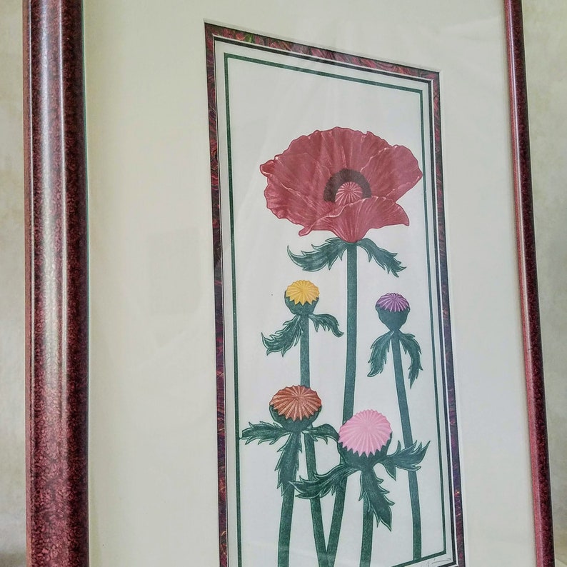 May include: Framed print of a red poppy flower with five smaller flowers in shades of pink, yellow, and purple. The flowers are depicted in a stylized, almost geometric, manner.