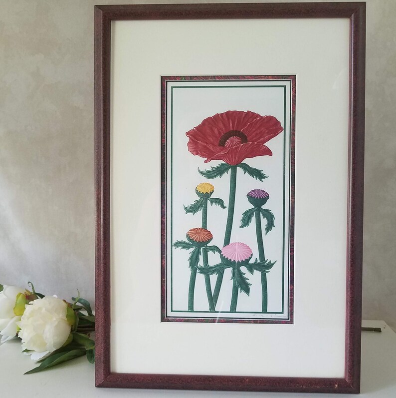 May include: Framed art print featuring a red poppy flower with five smaller flowers in shades of pink, yellow, and orange. The flowers are depicted in a stylized, almost cartoon-like manner, with thick stems and leaves.
