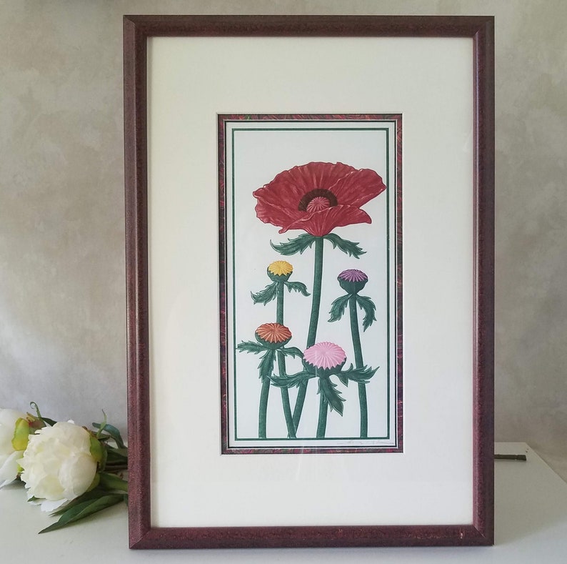 May include: Framed art print of a red poppy flower with five smaller flowers in various colors, including yellow, pink, and purple. The flowers are depicted in a stylized, almost graphic, manner.