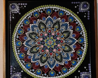 10x10 inch painted canvas. Dot mandala design in red, blue, green gold, purple and white. Swarovski crystals for sparkle. Gold frame.